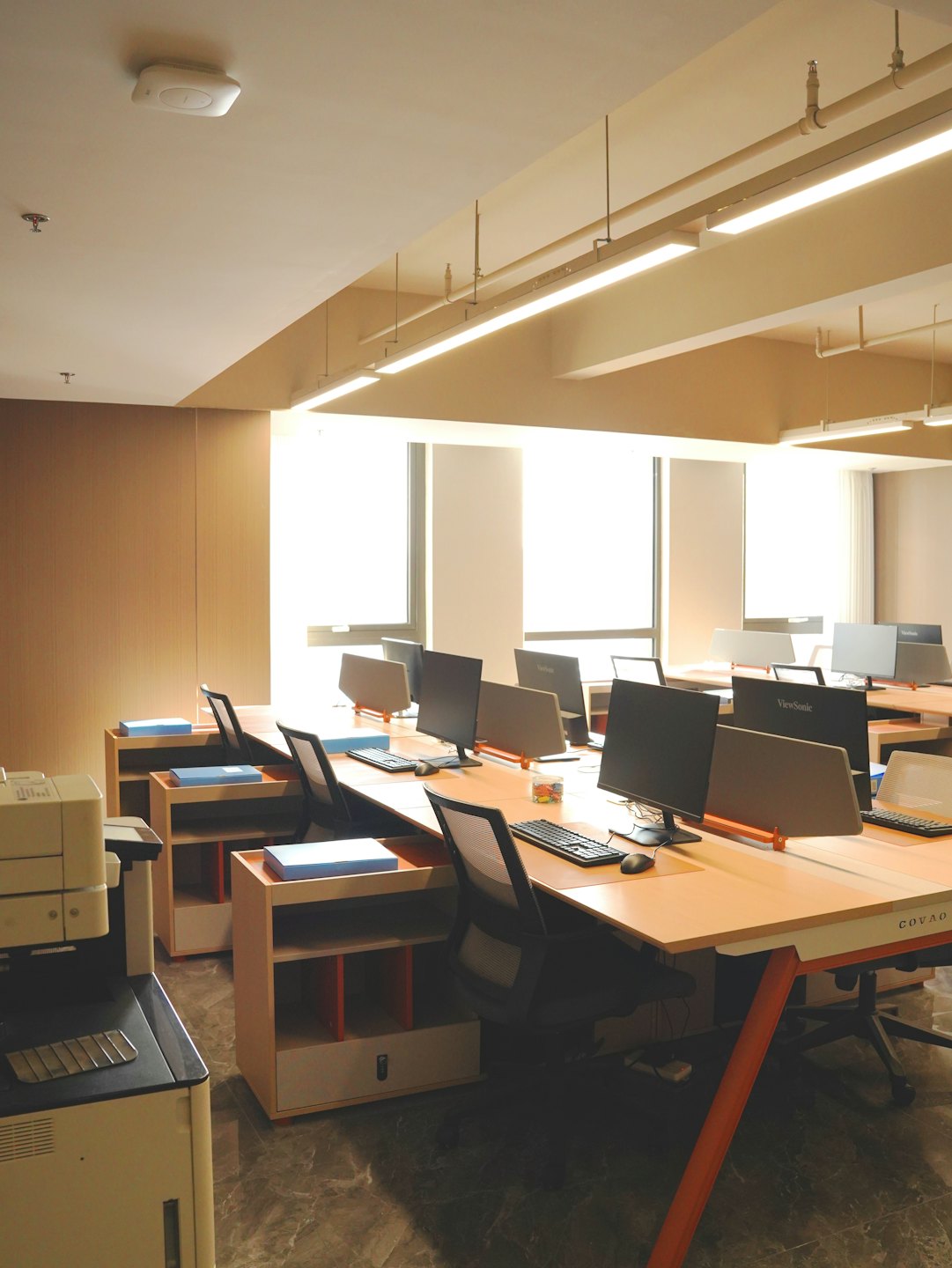 Modern office interior featuring wooden desks and large windows.